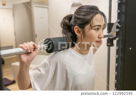 在室內健身房進行肌肉訓練的年輕女子 在室內健身房進行肌肉訓練的年輕女子 122992595