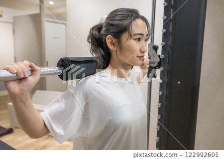 在室內健身房進行肌肉訓練的年輕女子 在室內健身房進行肌肉訓練的年輕女子 122992601
