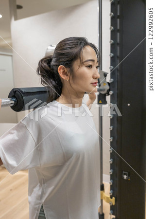 Young woman doing muscle training in indoor gym Young woman doing muscle training in indoor gym 122992605