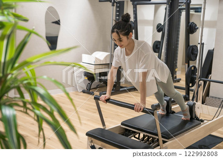 在室內健身房做機器普拉提的年輕女子 在室內健身房做機器普拉提的年輕女子 122992808