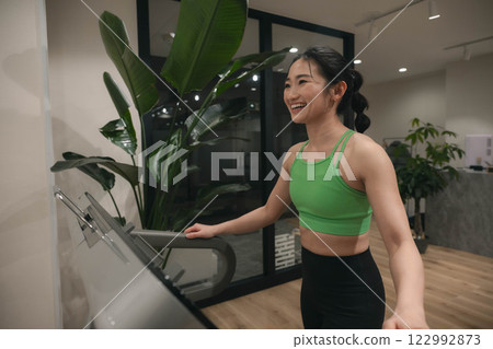 一名身穿訓練服的年輕女子在健身房跑步 122992873