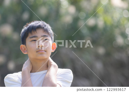 男孩雙手放在脖子上盯著 男孩雙手放在脖子上盯著 122993617