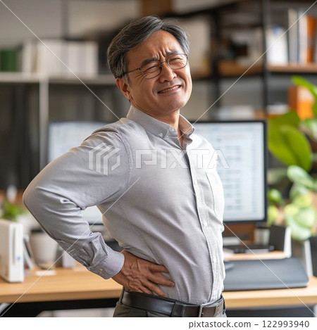A middle-aged male office worker suffering from back pain 122993940