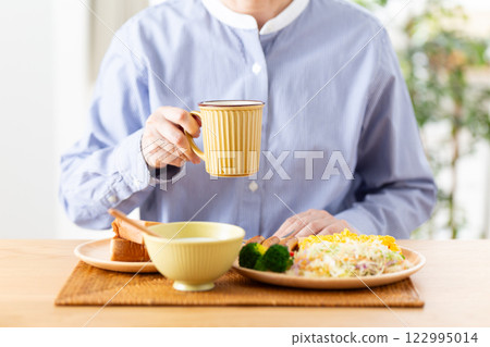 Middle-aged woman eating a Western-style breakfast Middle-aged woman eating a Western-style breakfast 122995014