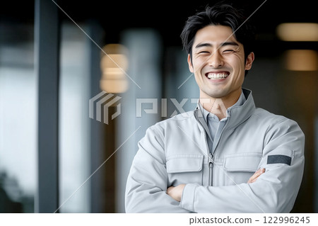 A male worker in work clothes smiling with his arms folded 122996245