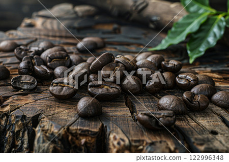 Dark roasted coffee beans scattered on rustic wooden surface, texture, aroma, and the essence of coffee culture 122996348