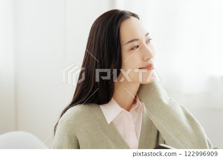 Businesswoman sitting at a table and looking out the window in her office 122996909