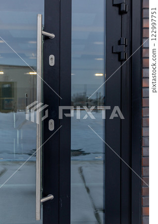 A Contemporary Modern Glass Door that Features a Sleek Stainless Steel Handle System 122997751