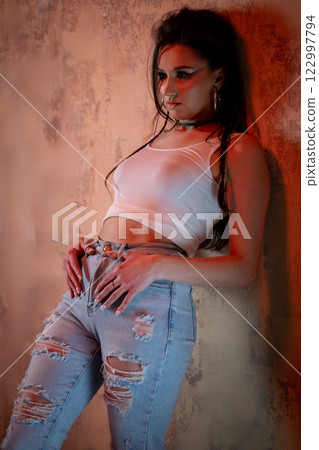 A Stylish Young Woman Posing Confidently in Trendy Ripped Jeans and a Chic Crop Top A Stylish Young Woman Posing Confidently in Trendy Ripped Jeans and a Chic Crop Top 122997794