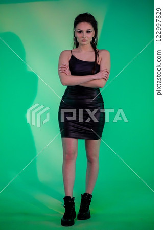 A Stylish Woman Dressed in a Black Dress Poses Elegantly Against a Stylish Green Background 122997829
