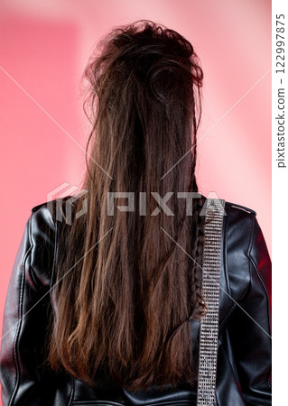 A Stylish Individual with Long Hair Wearing a Black Leather Jacket That Commands Attention 122997875