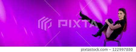 A Stylish Fashionable Model in Elegant High Heels Posing Against a Vibrant Purple Background 122997880