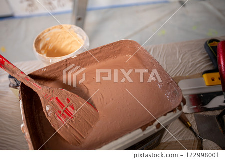 Learn to mix brown paint effectively with a spatula to achieve desired color and texture 122998001