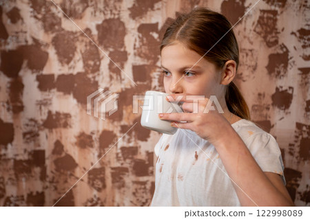 A Child Delightfully Enjoying a Warm Beverage While Seated Against a Textured Background A Child Delightfully Enjoying a Warm Beverage While Seated Against a Textured Background 122998089