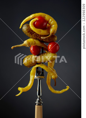 Canned yellow peppers, cucumbers, and tomatoes on a black background. 122998309
