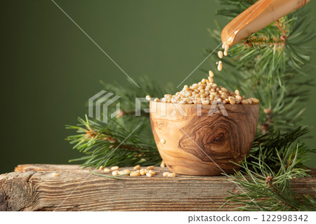 Pine nuts is poured in a wooden bowl. Pine nuts is poured in a wooden bowl. 122998342