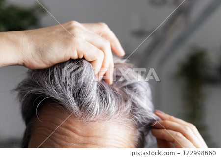 Close up head of an adult elderly woman with gray hair. Hands sort through hair. Concept anti aging. Close up head of an adult elderly woman with gray hair. Hands sort through hair. Concept anti aging. 122998660