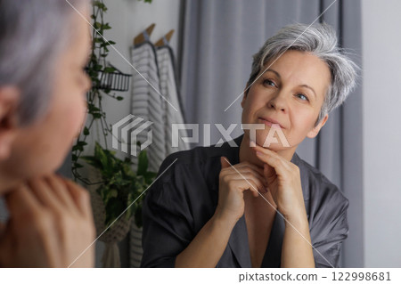 An adult well-groomed beautiful woman of age during menopause with gray hair does self-care An adult well-groomed beautiful woman of age during menopause with gray hair does self-care 122998681