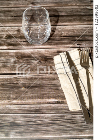 knife, fork and a transparent glass on top of a wooden table 122998682