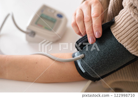Woman at home trying to fight migraine and headache and measures blood pressure with tonometer 122998710