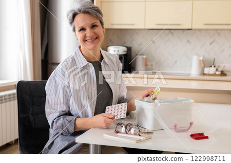 Beautiful, well-groomed and aged woman pensioner aged with gray hairchecking medicines  122998711