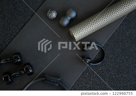 Sports massagers manual and electric in the gym on a mat of black color. And also dumbbells  122998755