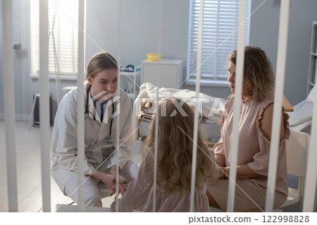 A doctor discusses treatment options with a patient and their mother in the hospital A doctor discusses treatment options with a patient and their mother in the hospital 122998828