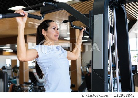 Young beautiful Asian woman with athletic build and good figure doing pull-ups Young beautiful Asian woman with athletic build and good figure doing pull-ups 122998842