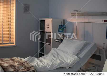 A contemporary hospital room equipped with an adjustable bed and generous natural light streams in 122998852