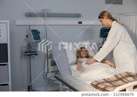 A compassionate nurse providing attentive care for a sick child in a hospital room setting 122998870