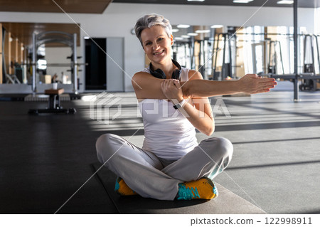 Athletic fitness An elderly gray-haired senior pensioner of age stretching body at gym 122998911