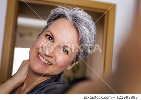 An adult well-groomed beautiful woman of age during menopause with gray hair takes a selfie  122998988
