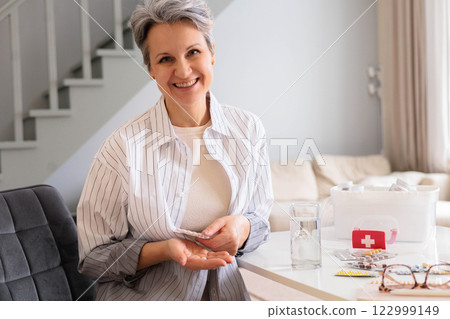 A beautiful elderly woman pensioner with gray hair is going to take a headache pill A beautiful elderly woman pensioner with gray hair is going to take a headache pill 122999149