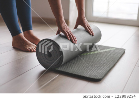 Yoga woman folding roll mat before after meditation practice training at home closeup 122999254