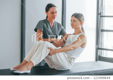 Doing abs. Woman is in health center getting help by doctor Doing abs. Woman is in health center getting help by doctor 122999644