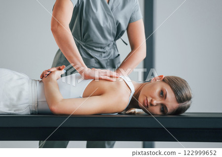 Professional massage. Woman is in health center getting help by doctor Professional massage. Woman is in health center getting help by doctor 122999652