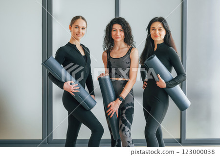 Holding yoga mats. Women in sportive clothes standing in the fitness center 123000038