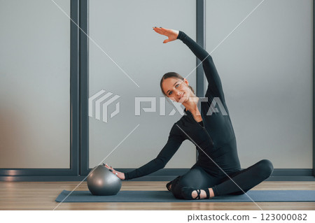 Sitting on yoga mat. Woman in sportive clothes is in the studio 123000082