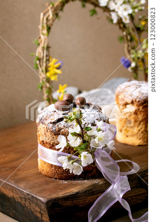 Homemade Italian traditional Easter panettone cake, decorated by chocolate eggs, pink ribbon and blossoming cherry tree flowers standing on wooden table. Traditional Easter European bake. Homemade Italian traditional Easter panettone cake, decorated by chocolate eggs, pink ribbon and blossoming cherry tree flowers standing on wooden table. Traditional Easter European bake. 123000823