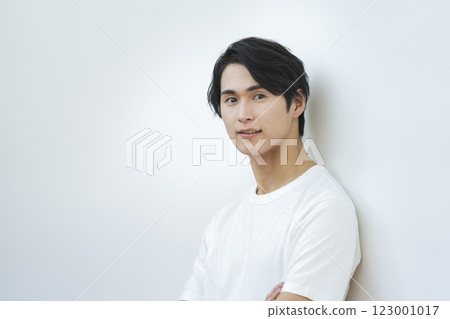一位 20 多歲的男子身穿白色 T 卹看著鏡頭 男士美容護膚圖像肖像 123001017