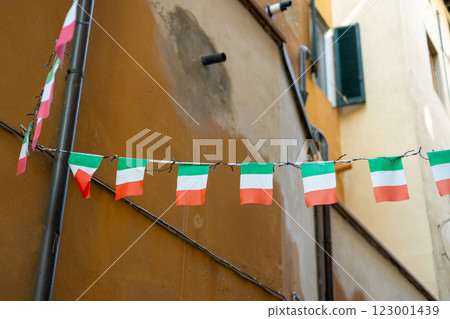 Typical street with houses in Italy. Facade of a yellow building with Italian flags. Italian flag in an old town narrow street of a city in Italy 123001439