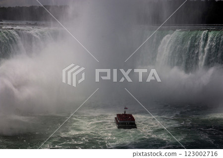 Boat Approaches Niagara Falls Amidst Mist and Powerful Water Flow 123002716