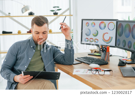 With tablet in hands. Male designer working in the office by using PC With tablet in hands. Male designer working in the office by using PC 123002817