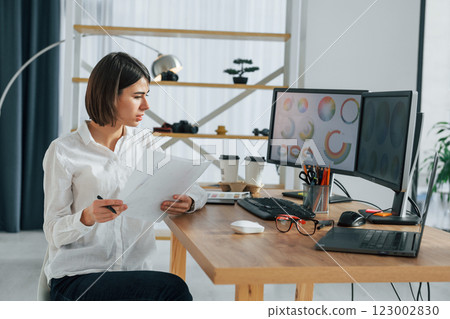 Looking at display. Female designer working in the office by using PC Looking at display. Female designer working in the office by using PC 123002830
