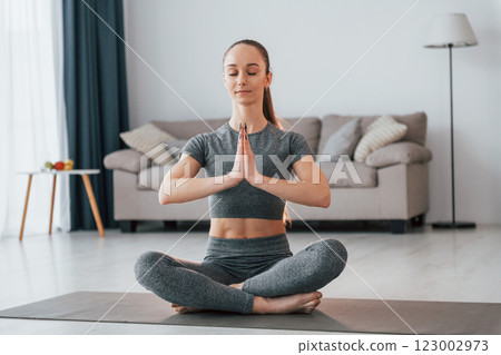 Lotus pose. Young woman with slim body type and in yoga clothes is at home Lotus pose. Young woman with slim body type and in yoga clothes is at home 123002973