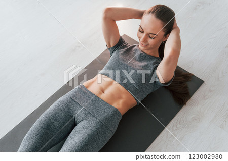 On the mat. Young woman with slim body type and in yoga clothes is at home On the mat. Young woman with slim body type and in yoga clothes is at home 123002980