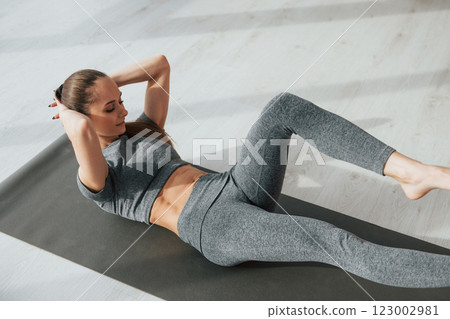 On the mat. Young woman with slim body type and in yoga clothes is at home On the mat. Young woman with slim body type and in yoga clothes is at home 123002981