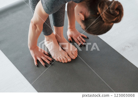 Close up view. Young woman with slim body type and in yoga clothes is at home 123003008