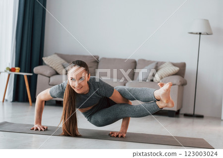 Exercises for stamina. Young woman with slim body type and in yoga clothes is at home 123003024