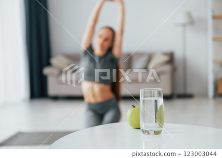 With glass of water. Young woman with slim body type and in yoga clothes is at home 123003044